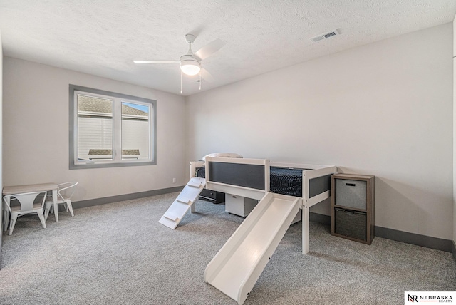 carpeted bedroom featuring visible vents, baseboards, a textured ceiling, and a ceiling fan