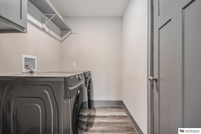 washroom featuring wood finished floors, cabinet space, independent washer and dryer, and baseboards