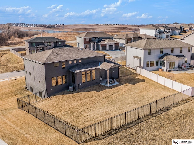 exterior space featuring a residential view, central AC, a fenced backyard, and a front lawn