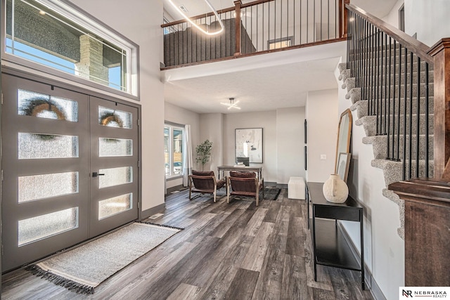 entrance foyer featuring stairway, baseboards, a high ceiling, dark wood-type flooring, and french doors