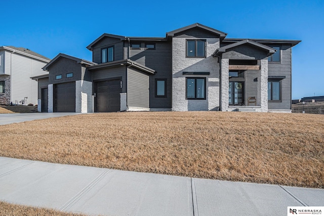 view of front of home with stone siding, a garage, concrete driveway, and a front lawn