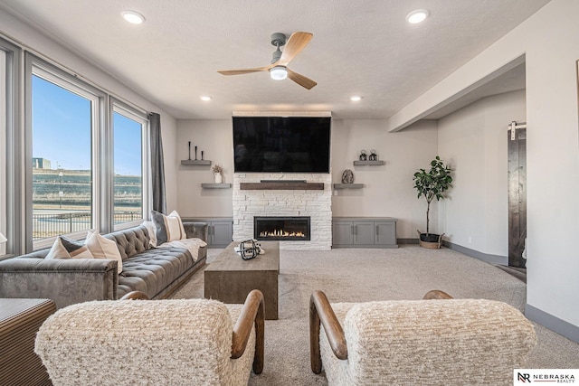 living area with a fireplace, a ceiling fan, carpet floors, and a textured ceiling