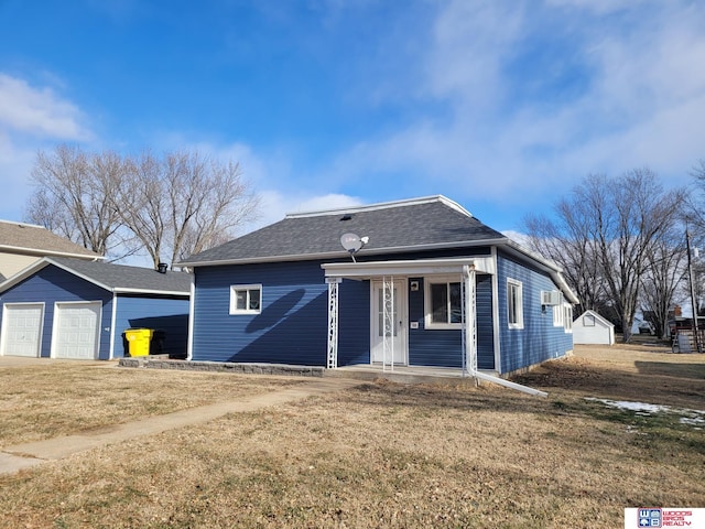 view of front of home with a shingled roof, a front yard, a porch, and a garage