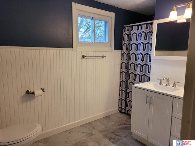 bathroom featuring marble finish floor, a wainscoted wall, curtained shower, toilet, and vanity