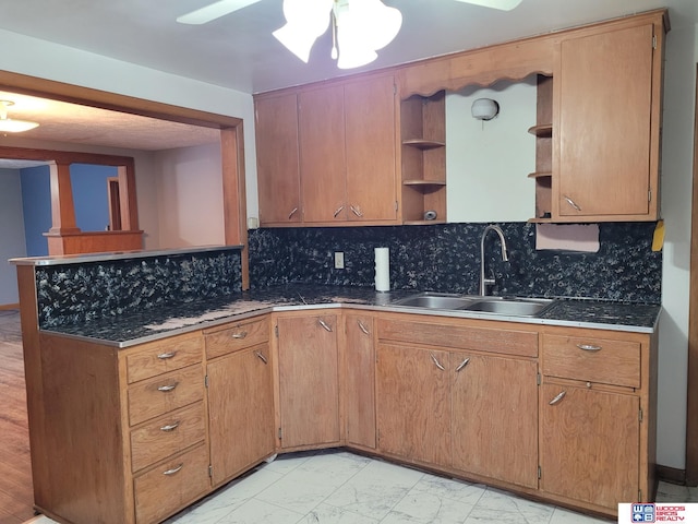 kitchen with a peninsula, marble finish floor, a sink, open shelves, and backsplash