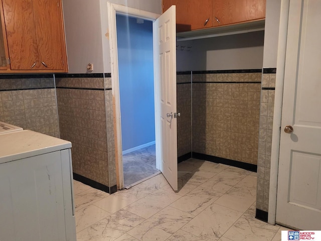 bathroom with a wainscoted wall, marble finish floor, washer / clothes dryer, and tile walls