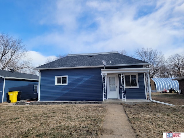 view of front of home with covered porch, roof with shingles, and a front lawn