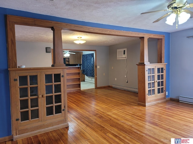 unfurnished living room featuring a baseboard heating unit, a textured ceiling, wood-type flooring, and a ceiling fan