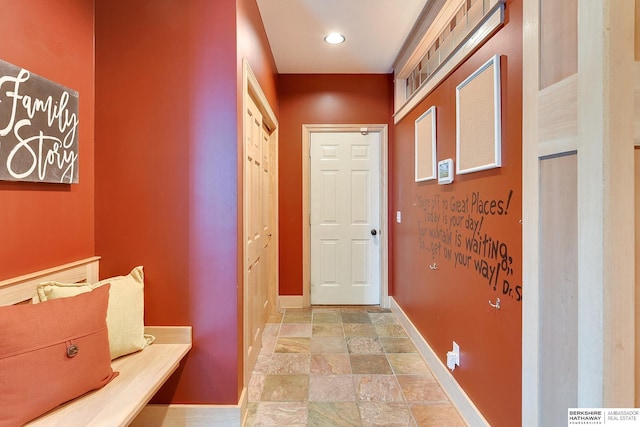 hallway featuring stone finish flooring and baseboards