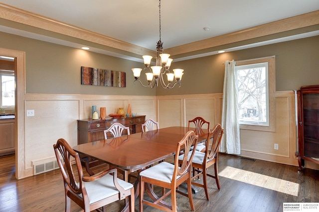 dining space with dark wood finished floors, an inviting chandelier, and visible vents