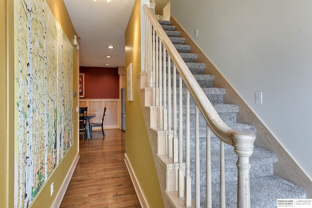 stairs featuring recessed lighting, wood finished floors, and wainscoting