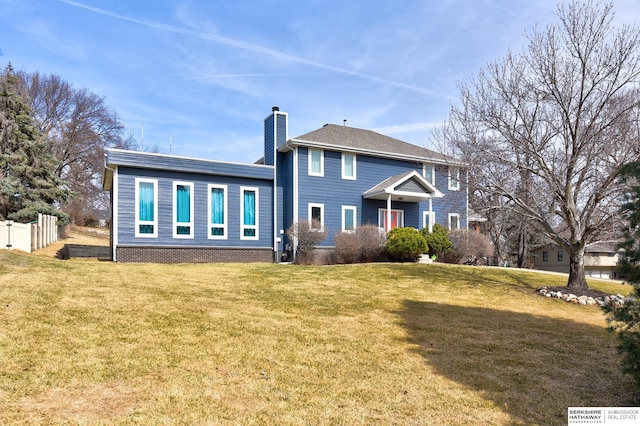 back of house with fence, a lawn, and a chimney