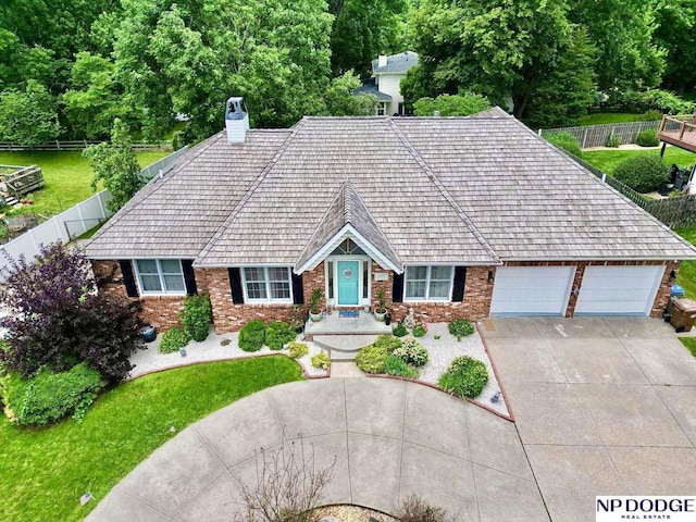 view of front of property featuring a chimney, an attached garage, concrete driveway, and fence