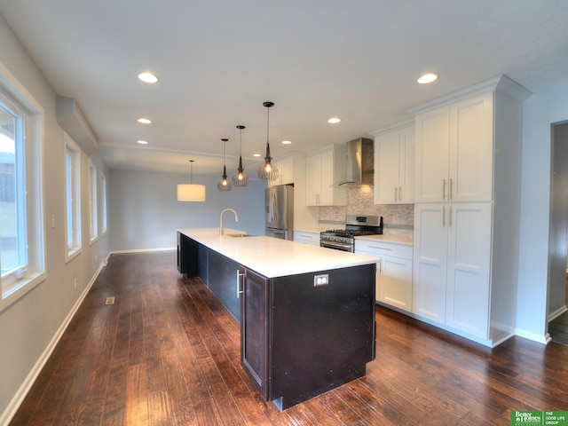 kitchen with a center island with sink, wall chimney exhaust hood, stainless steel appliances, light countertops, and a sink