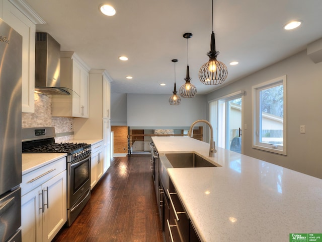 kitchen featuring white cabinets, appliances with stainless steel finishes, wall chimney exhaust hood, tasteful backsplash, and dark wood finished floors