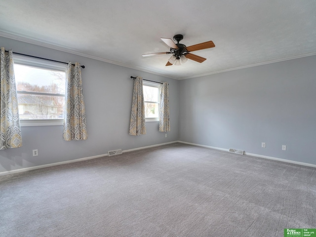 carpeted spare room with baseboards, visible vents, a ceiling fan, and ornamental molding