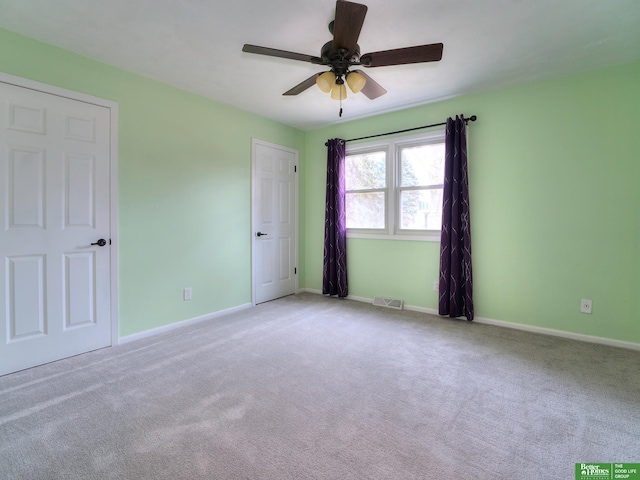 carpeted empty room featuring a ceiling fan, visible vents, and baseboards