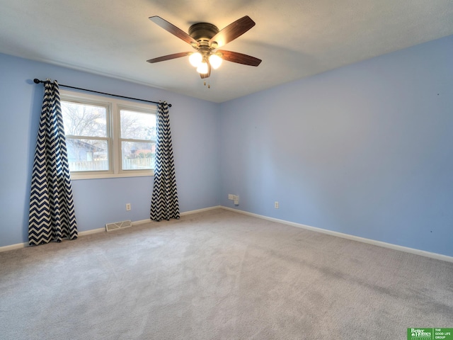 carpeted empty room with a ceiling fan, visible vents, and baseboards