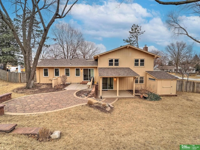 rear view of house featuring a patio, a shingled roof, a chimney, and fence