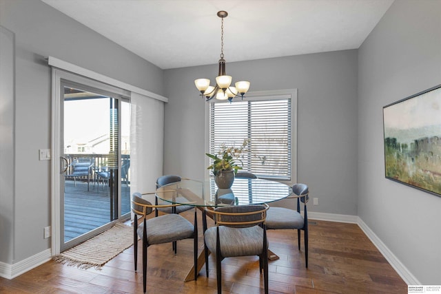 dining area with baseboards, an inviting chandelier, and wood finished floors