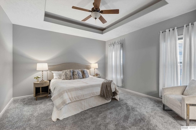 bedroom with carpet floors, a raised ceiling, and baseboards