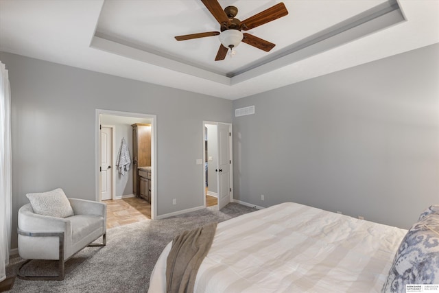 bedroom featuring light colored carpet, a ceiling fan, visible vents, baseboards, and a raised ceiling