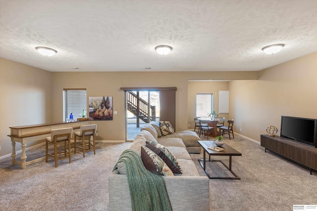 living area featuring carpet floors, baseboards, and a textured ceiling