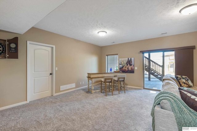 dining area with a textured ceiling, carpet flooring, visible vents, and baseboards