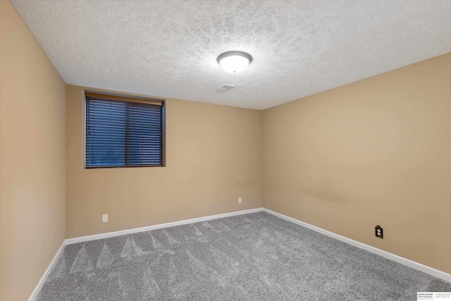 carpeted empty room featuring a textured ceiling and baseboards