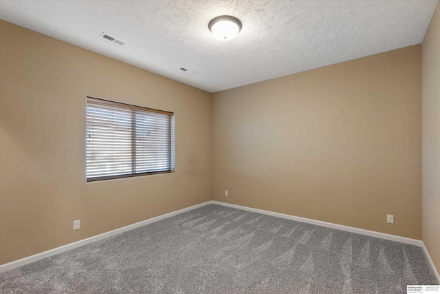 unfurnished room featuring baseboards, visible vents, dark carpet, and a textured ceiling