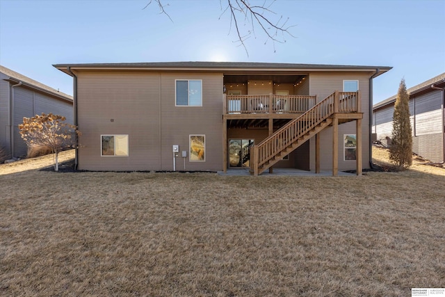 rear view of property featuring a lawn, a deck, and stairs