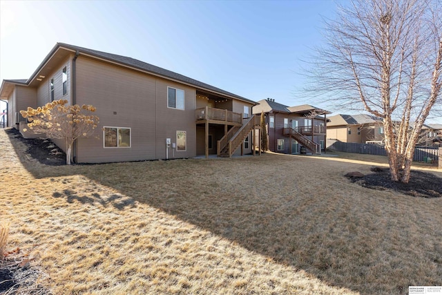 back of property with stairs, fence, a deck, and a lawn