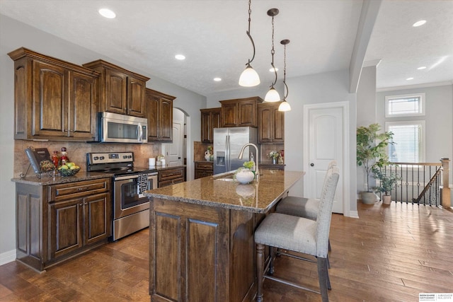 kitchen featuring arched walkways, stainless steel appliances, tasteful backsplash, and dark wood finished floors