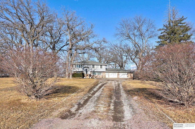 view of front of property with a garage, driveway, a front lawn, and stone siding