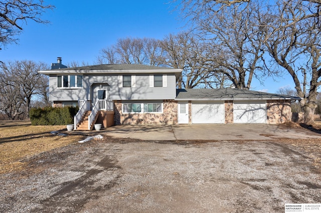 bi-level home with a garage, a chimney, and concrete driveway