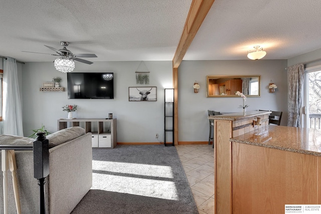 kitchen with a textured ceiling, baseboards, light tile patterned flooring, and light stone countertops