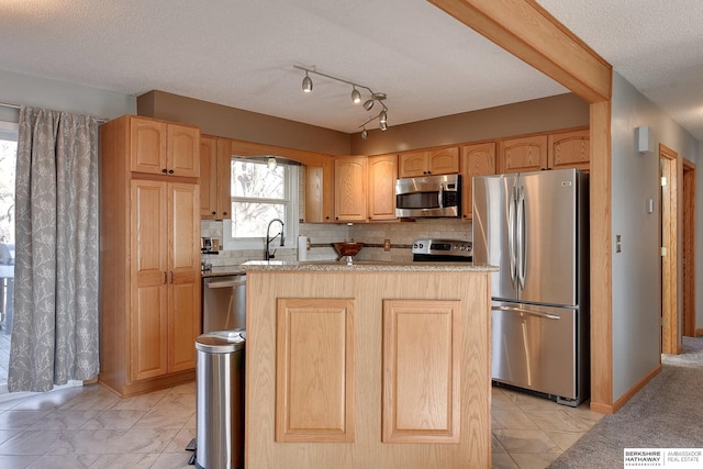 kitchen featuring appliances with stainless steel finishes, a kitchen island, a sink, and tasteful backsplash