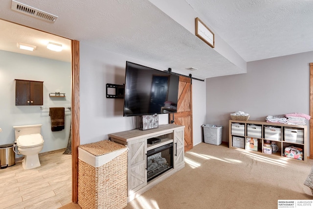 living area with a barn door, visible vents, and a textured ceiling