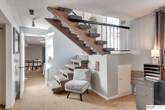 staircase with baseboards, a textured ceiling, visible vents, and carpet flooring