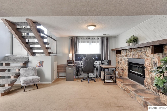 office with a textured ceiling, a stone fireplace, carpet, and baseboards