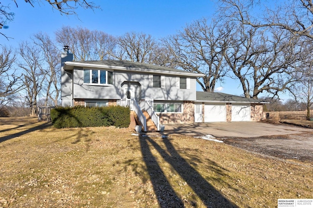 bi-level home with a garage, a front yard, driveway, and a chimney