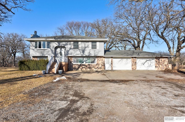 bi-level home featuring a garage, driveway, and a chimney