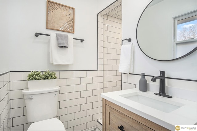 bathroom featuring toilet, vanity, and tile walls