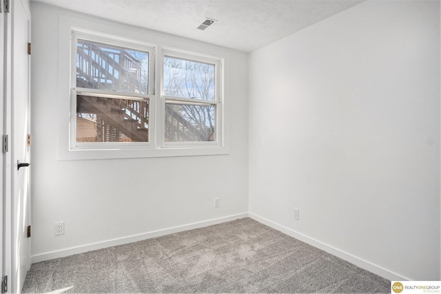 carpeted spare room featuring visible vents, baseboards, and a textured ceiling