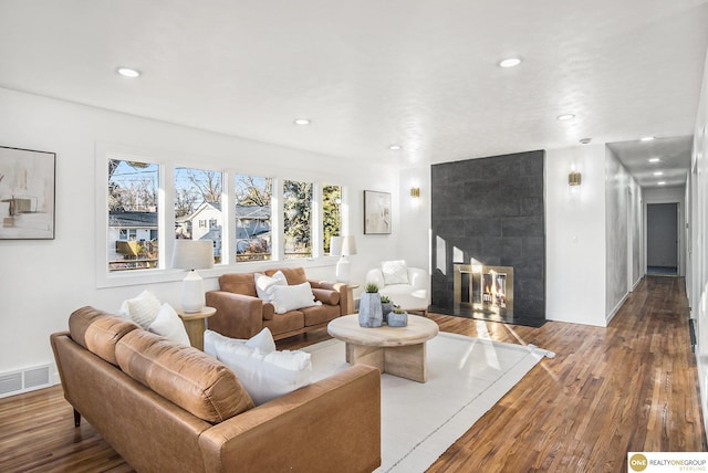 living room featuring recessed lighting, visible vents, a tiled fireplace, and wood finished floors