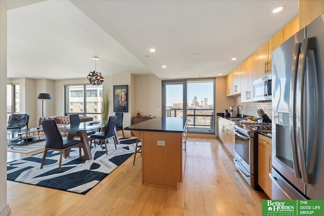 kitchen featuring dark countertops, a kitchen island, stainless steel appliances, light wood-type flooring, and a sink