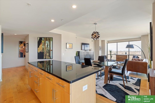 kitchen featuring dark countertops, modern cabinets, open floor plan, a center island, and light wood-style floors