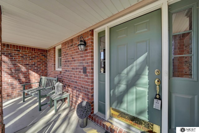 entrance to property featuring covered porch and brick siding