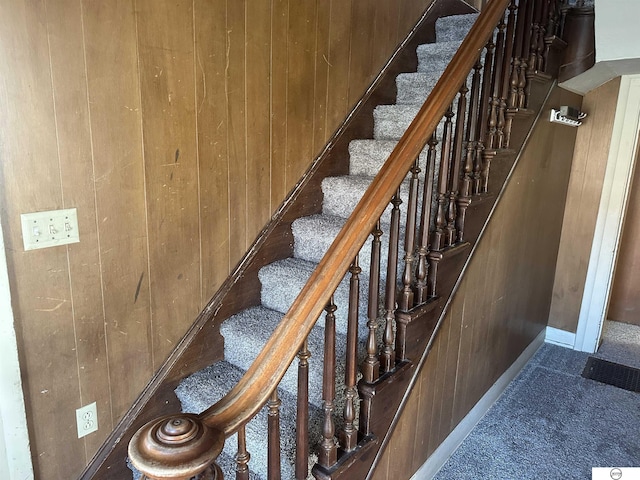 stairway featuring wood walls and carpet