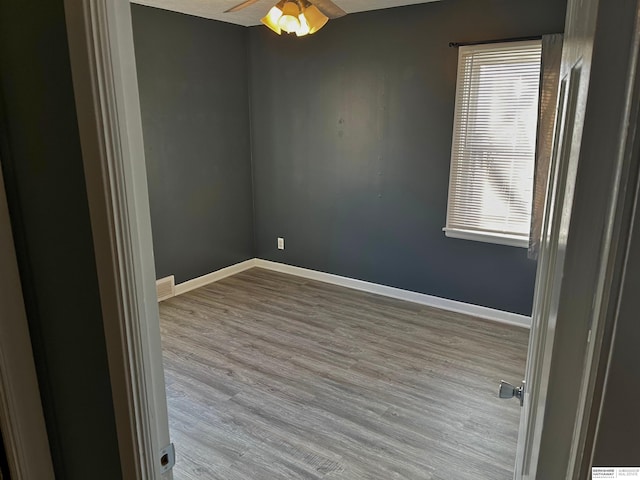 empty room featuring a ceiling fan, baseboards, and wood finished floors